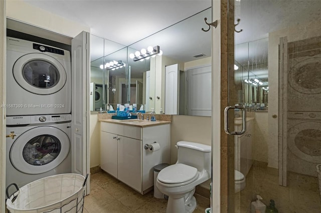 bathroom featuring an enclosed shower, stacked washer and dryer, tile floors, toilet, and vanity