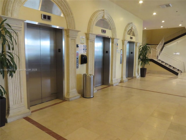 corridor with elevator, decorative columns, and visible vents