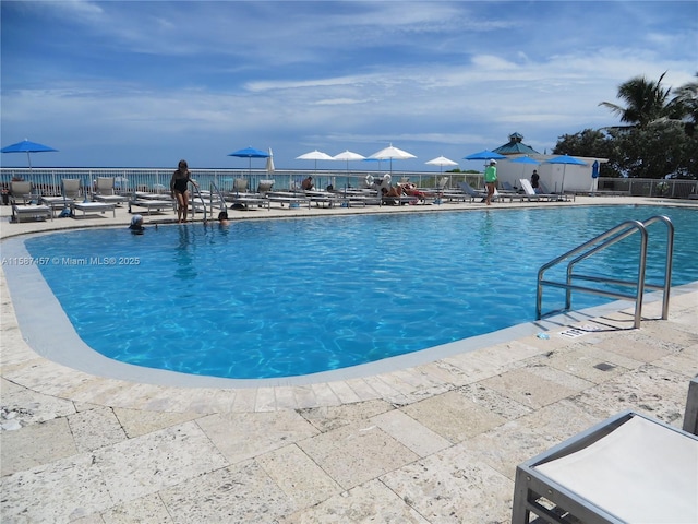 community pool with a patio and fence