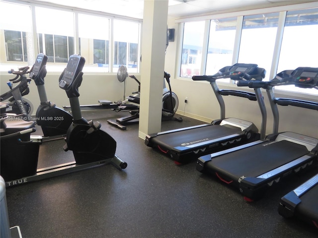 exercise room featuring a healthy amount of sunlight and baseboards