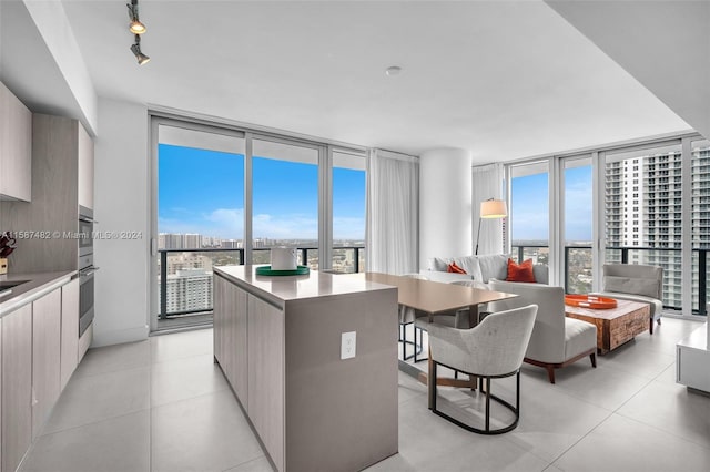 kitchen featuring track lighting, light tile flooring, a wall of windows, and a kitchen island