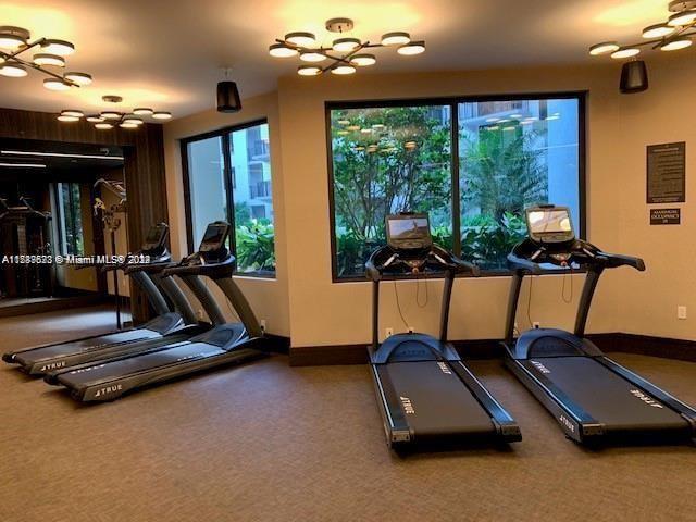 exercise room featuring carpet flooring, baseboards, and a chandelier