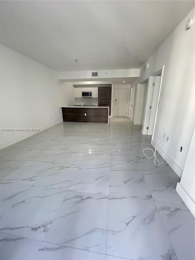 unfurnished living room featuring marble finish flooring and baseboards