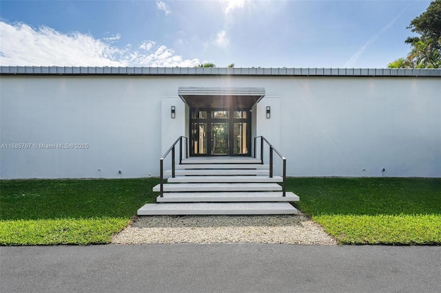 view of exterior entry featuring a lawn