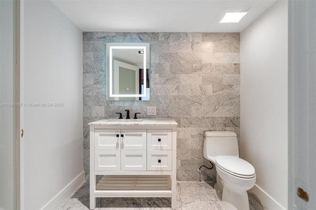 bathroom featuring vanity, toilet, and tile walls