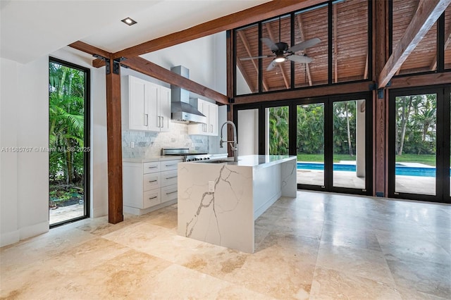 kitchen with sink, white cabinetry, tasteful backsplash, an island with sink, and a wealth of natural light