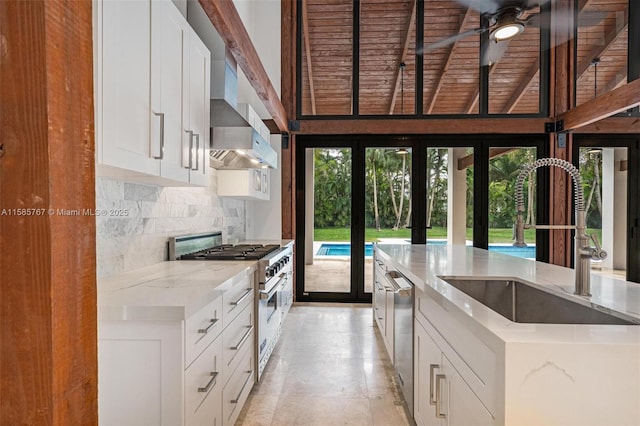 kitchen featuring tasteful backsplash, white cabinetry, sink, stainless steel appliances, and light stone countertops