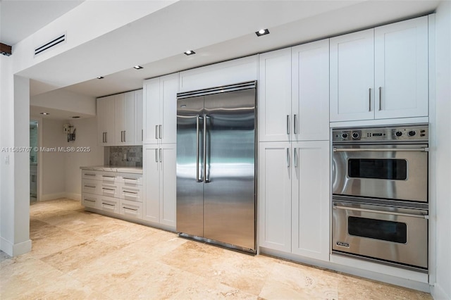 kitchen featuring white cabinetry, appliances with stainless steel finishes, and decorative backsplash