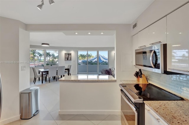 kitchen featuring light stone countertops, tasteful backsplash, electric stove, light tile floors, and white cabinetry