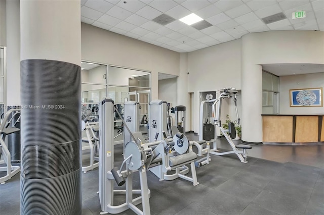 workout area with a towering ceiling and a paneled ceiling