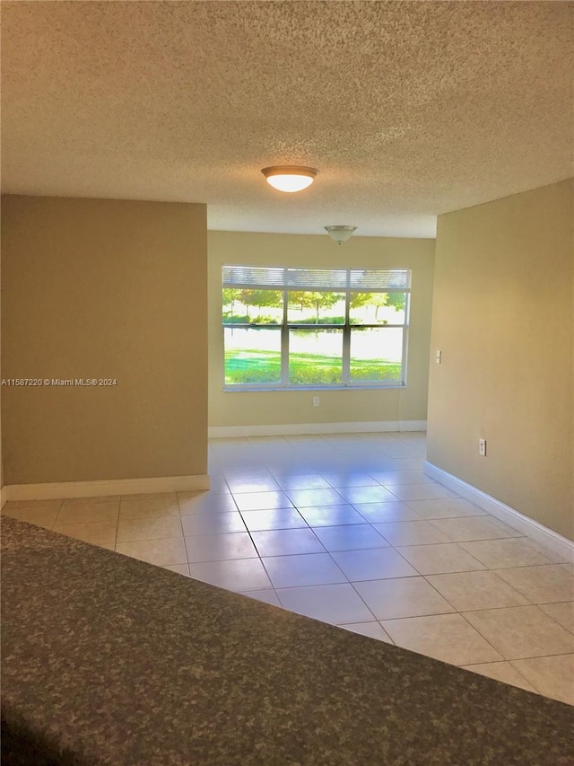 unfurnished room with tile floors and a textured ceiling