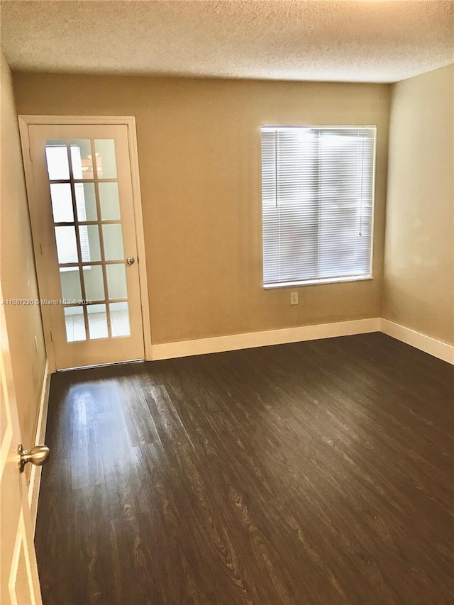 unfurnished room featuring dark hardwood / wood-style flooring and a textured ceiling