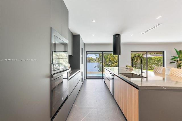 kitchen featuring sink, light tile patterned floors, a spacious island, black electric cooktop, and stainless steel dishwasher