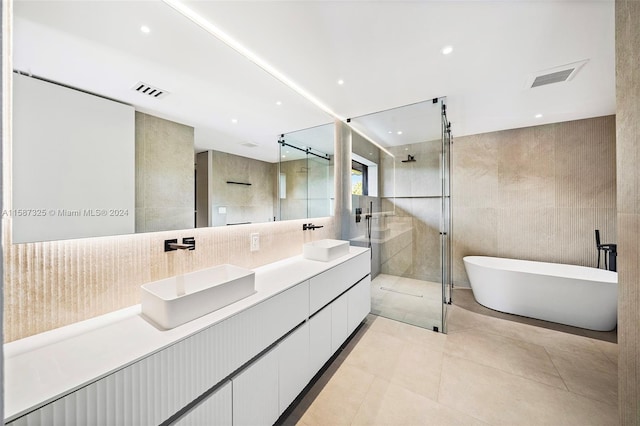 bathroom featuring tile patterned floors, vanity, independent shower and bath, and tile walls