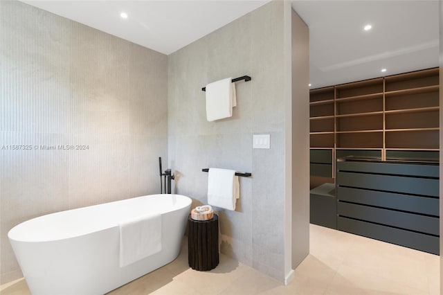 bathroom with tile walls, a tub to relax in, and tile patterned floors