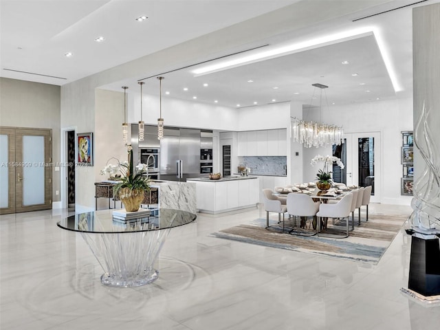 living room with a towering ceiling, french doors, an inviting chandelier, and light tile floors