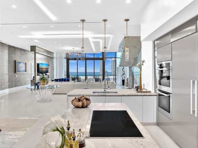 kitchen with a water view, white cabinets, hanging light fixtures, sink, and stainless steel double oven