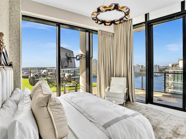 bedroom with an inviting chandelier, a water view, and multiple windows