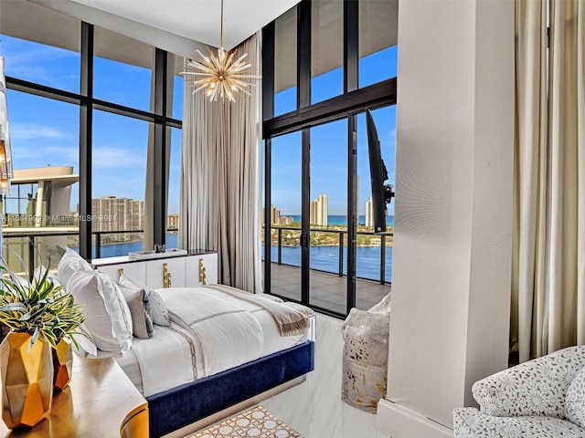 bedroom with an inviting chandelier, expansive windows, and a water view