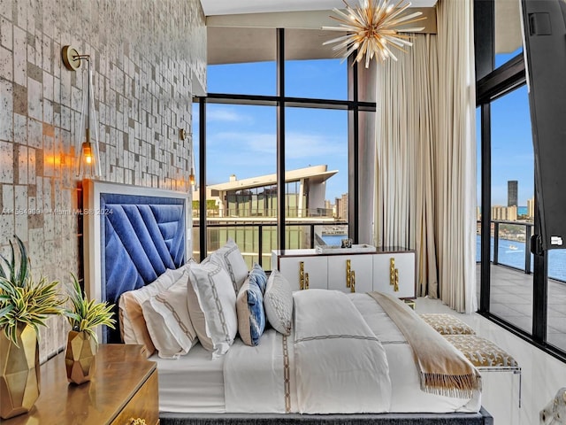 bedroom featuring multiple windows, a water view, and an inviting chandelier