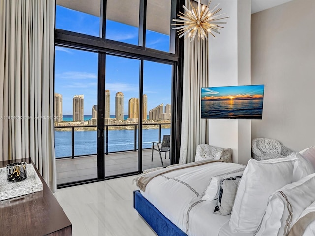 bedroom with access to exterior, multiple windows, a water view, and an inviting chandelier