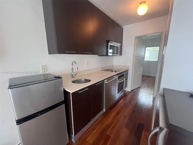 kitchen with dark wood-type flooring, stainless steel appliances, sink, and dark brown cabinets