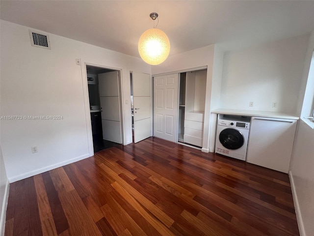 unfurnished bedroom with dark hardwood / wood-style flooring, washer / clothes dryer, and a closet