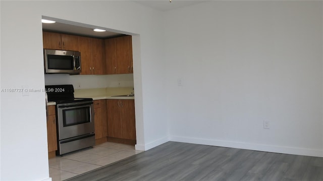 kitchen with light wood-type flooring, sink, and appliances with stainless steel finishes