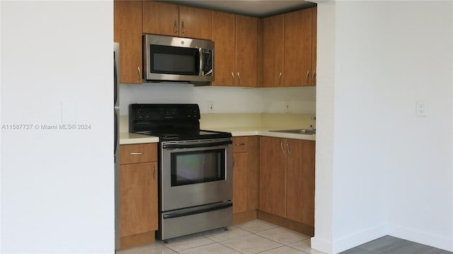 kitchen featuring appliances with stainless steel finishes, light tile patterned floors, and sink