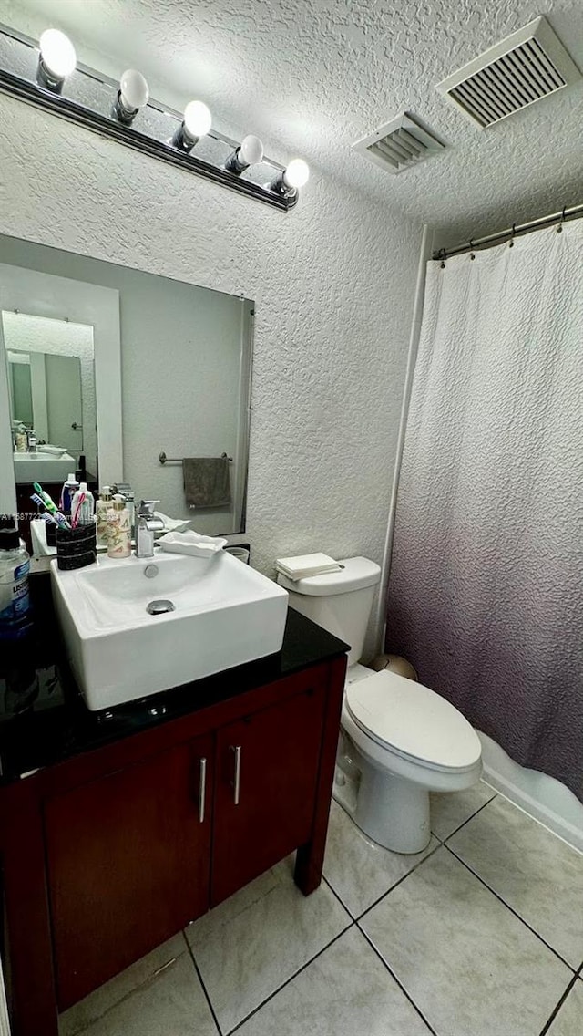 bathroom featuring toilet, walk in shower, tile patterned floors, vanity, and a textured ceiling