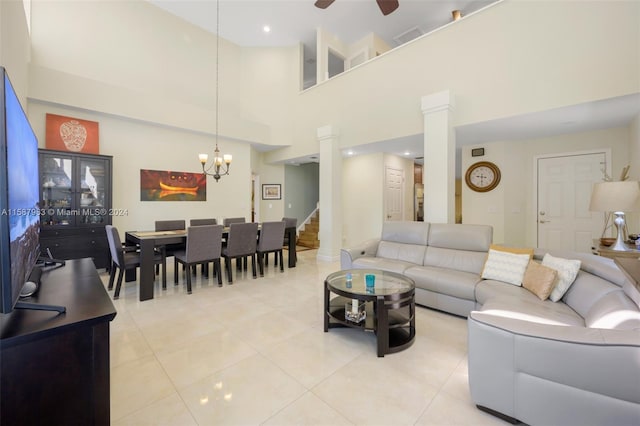 tiled living room with a high ceiling, decorative columns, and ceiling fan with notable chandelier