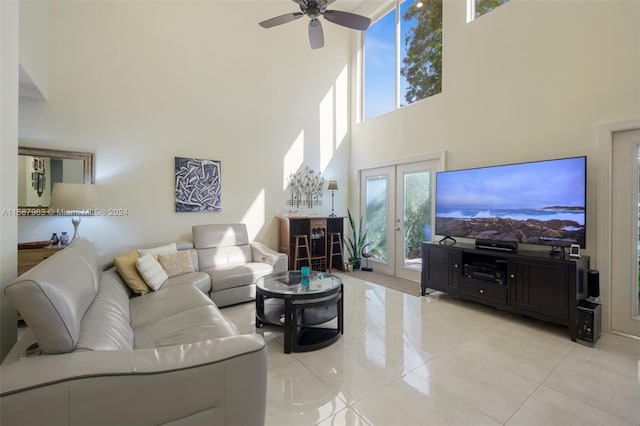 tiled living room with ceiling fan, a healthy amount of sunlight, a towering ceiling, and french doors