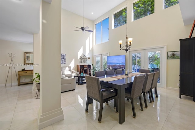 tiled dining area with a high ceiling, ceiling fan with notable chandelier, and french doors