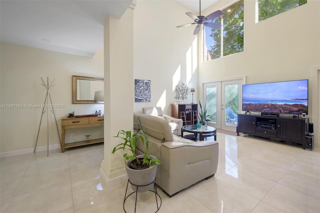 living room with a towering ceiling, french doors, ceiling fan, and light tile floors