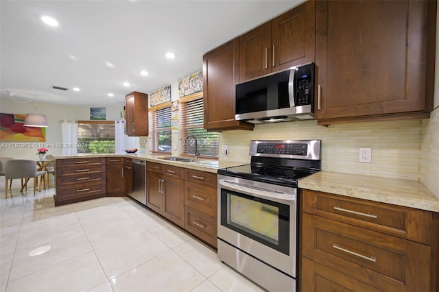 kitchen featuring appliances with stainless steel finishes, light stone counters, sink, tasteful backsplash, and light tile floors