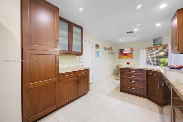 kitchen featuring dishwasher, light stone counters, backsplash, and light tile floors