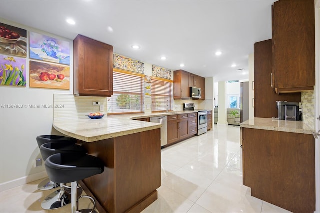 kitchen with a wealth of natural light, kitchen peninsula, backsplash, and appliances with stainless steel finishes