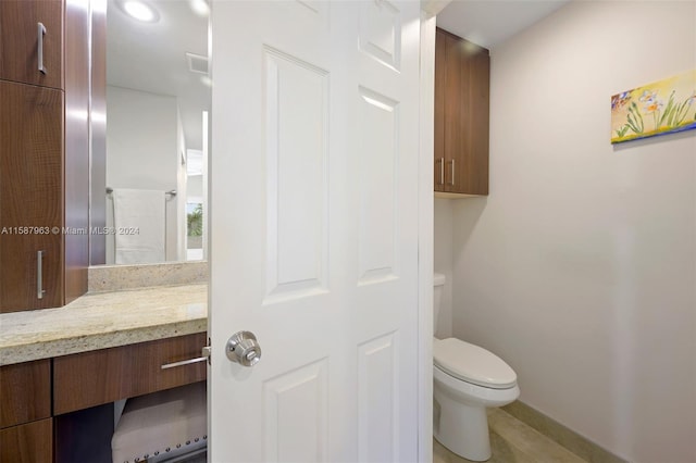 bathroom featuring tile flooring, large vanity, and toilet