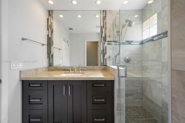 bathroom with a shower with shower door and vanity