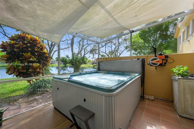 view of patio with a hot tub and a water view