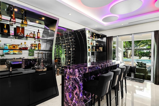 bar featuring light tile patterned flooring and a raised ceiling