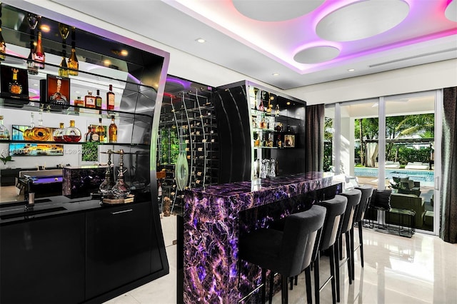 bar with tile patterned floors, a raised ceiling, and wet bar