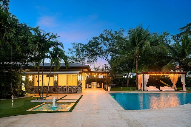 pool at dusk featuring an outdoor pool and a patio
