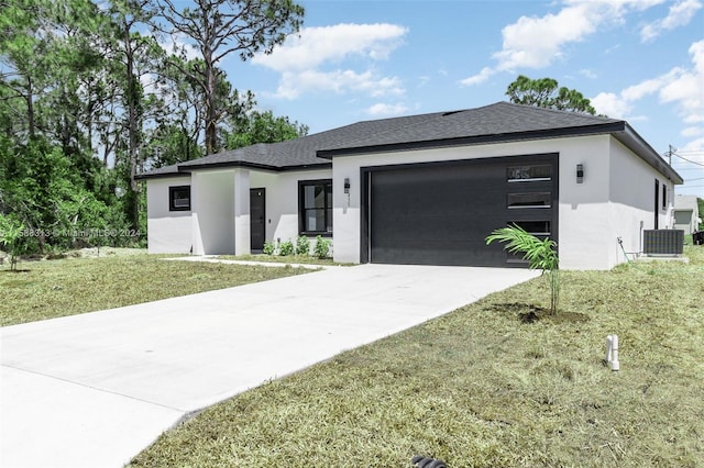 prairie-style home featuring a garage, cooling unit, and a front yard