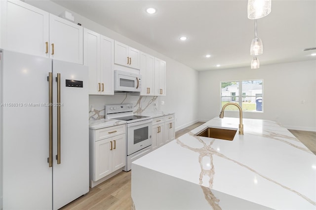 kitchen with light stone counters, white cabinets, sink, white appliances, and decorative light fixtures