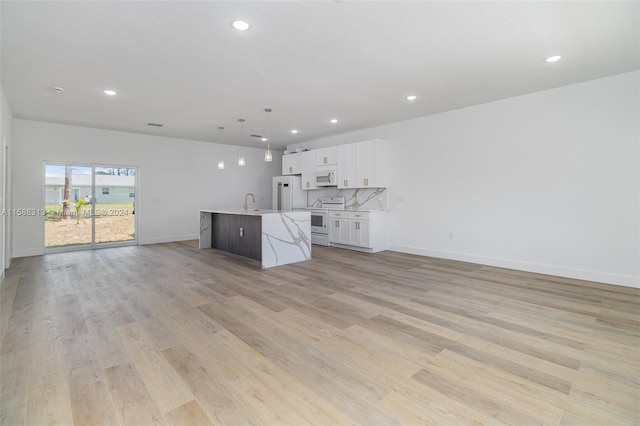 kitchen featuring hanging light fixtures, white appliances, a kitchen island with sink, white cabinetry, and light wood-type flooring