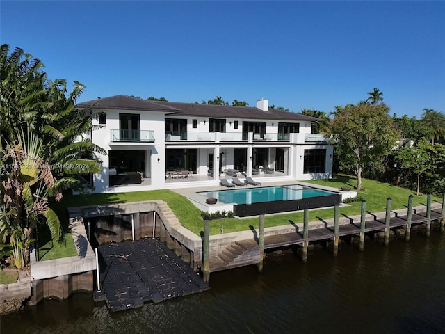 rear view of house with a yard, a water view, and a balcony