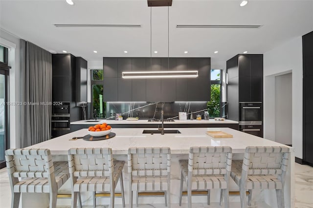 kitchen with a kitchen island with sink, tasteful backsplash, and a breakfast bar area