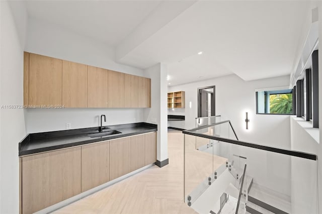 kitchen featuring light brown cabinets, sink, and light parquet flooring