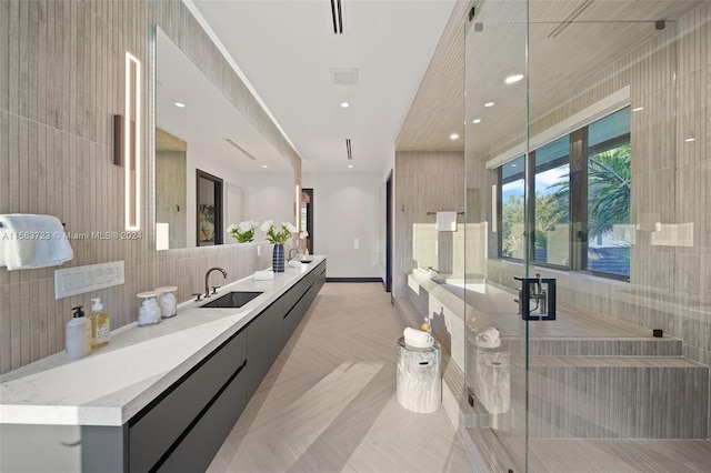 bathroom with double vanity, an enclosed shower, parquet flooring, and tile walls